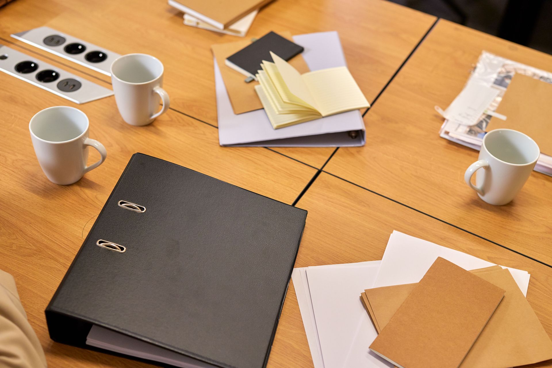 A neat office desk with binders, papers, and coffee mugs arranged neatly, offering a professional workspace vibe.